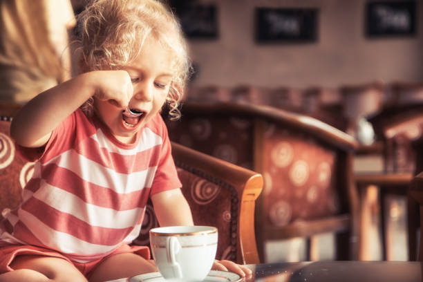 fille heureuse d'enfant buvant le thé dans le restaurant intérieur anglais traditionnel classique - five oclock tea photos et images de collection