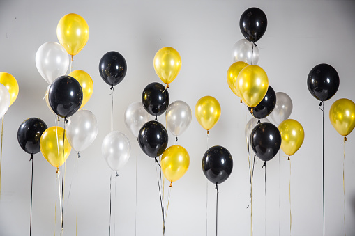 Set of black, yellow and white helium ball isolated in the air. Celebration background template with balloons