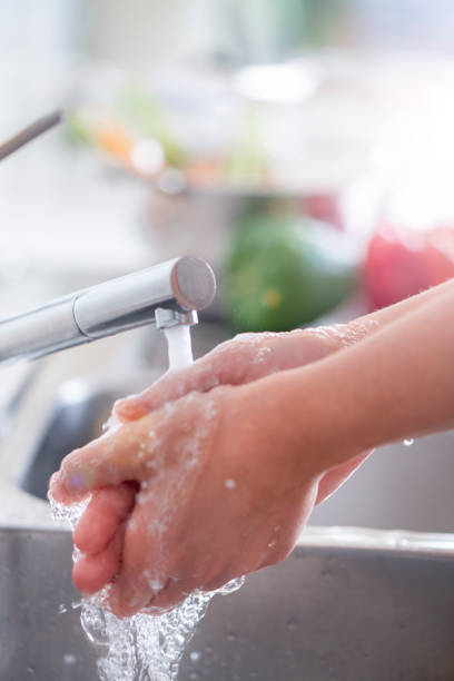istock Woman washing her hands at the kitchen sink. 1181710182