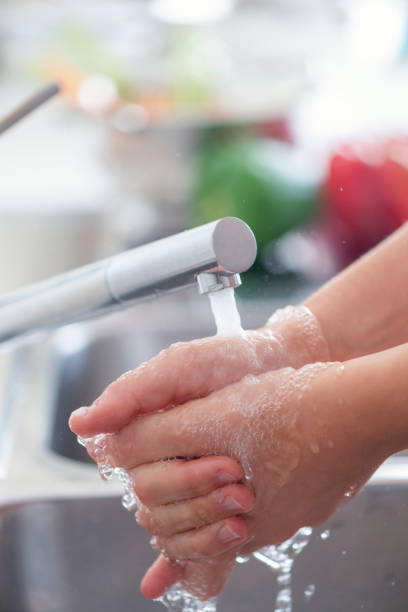 istock Woman washing her hands at the kitchen sink. 1181710183