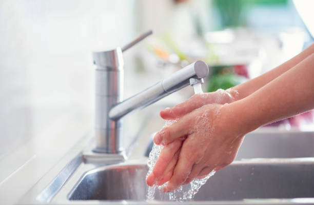 istock Woman washing her hands at the kitchen sink. 1181710185
