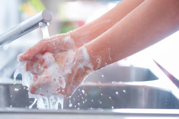 istock Woman washing her hands at the kitchen sink. 1181710190