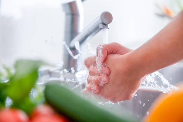 istock Woman washing her hands at the kitchen sink. 1181710196