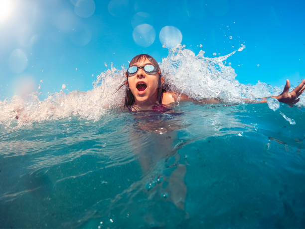 istock Girl swimming in turquoise water and getting splashed by the wave 1181714574