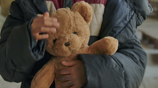 Close-up of dirty girl's hands holding teddy bear