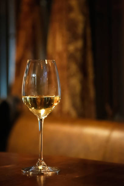 Glass of white wine in a restaurant Wineglass on the table in restaurant isolated on blurred background tungsten image stock pictures, royalty-free photos & images