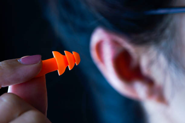 istock Female hand putting orange earplugs 1181724583