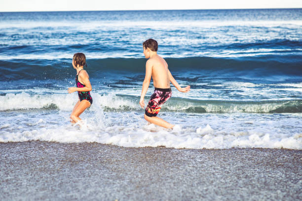 istock Siblings, three children, play in the ocean getting hit by waves 1181726336