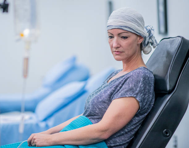 Woman Resting During IV Drip Cancer Treatment stock photo A woman resting while receiving her intravenous drip chemotherapy treatment hospital depression sadness bed stock pictures, royalty-free photos & images