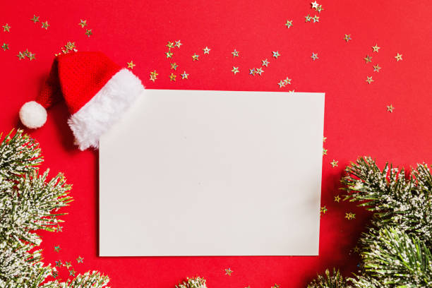 Paper blank, Christmas branches of fir, gift, Santa hat on red background with golden sparkles. Winter holidays, template, new year concept. Greeting card, xmas celebration 2020. Flat lay, top view, mockup en blanco de papel con sombrero de santa, regalo, ramas de árbol sobre fondo rojo con confeti dorado. concepto de año nuevo. tarjeta de felicitación, celebración de navidad 2020. plano, plantilla, vista superior, espacio de copia, maqueta