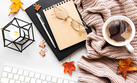 Autumn composition. Cup of coffee, women fashion sweater, dried leaves,  notebooks. Autumn, fall concept. Flat lay, top view, copy space