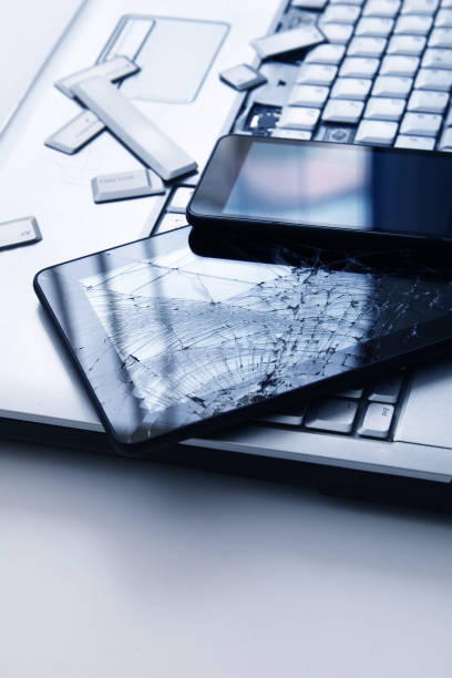 istock A silver laptop with a broken keyboard, tablet with a cracked display and black phone. A close-up picture of part of broken laptop and cracked screen on a tablet. 1181762329