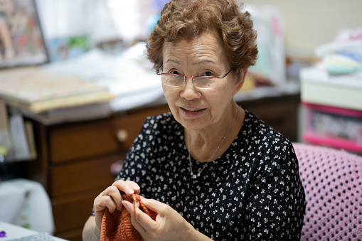 Elderly woman enjoying hobby knitting
