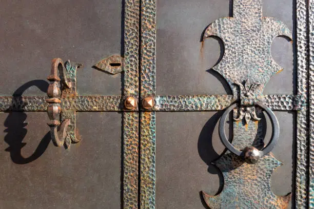 Fragment of old metal gate door. Handle, knocker and lock.