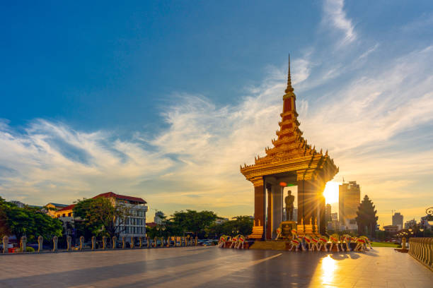 una estatua del rey padre norodom sihanouk con cielo azul y amarillo en el fondo de la puesta de sol por la noche en el centro de phnom penh, capital de camboya. - cambodia khmer architecture outdoors fotografías e imágenes de stock