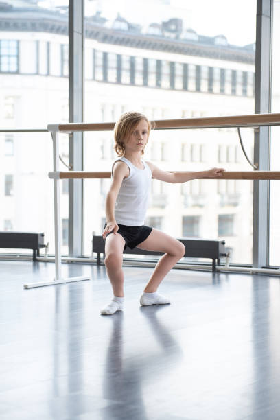 istock Young blond boy practicing ballet in a studio in white shirt and black underpants ballet uniform 1181788894