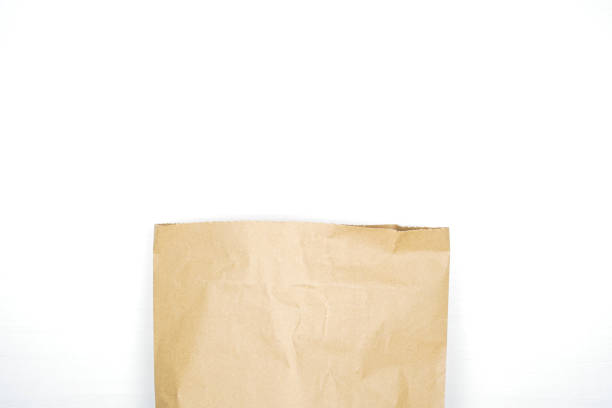 Brown paper bag on wooden white background with empty space for text. Flat lay, top view.