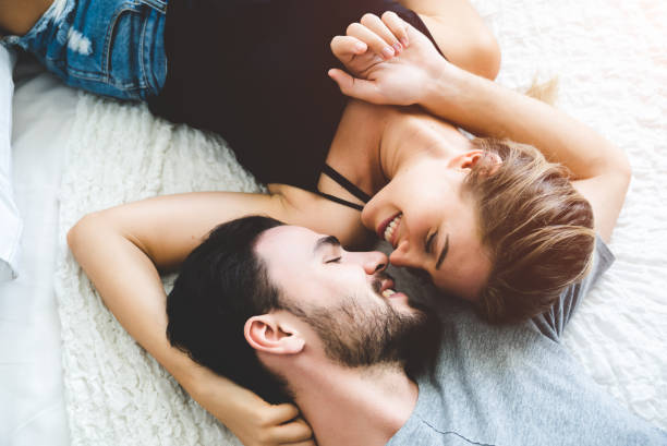 Passionate woman gently kissing man on with romantic kiss.desire lying on bed, young tender lover enjoys touching soft skin of sensual sexy lady moaning having sex. stock photo