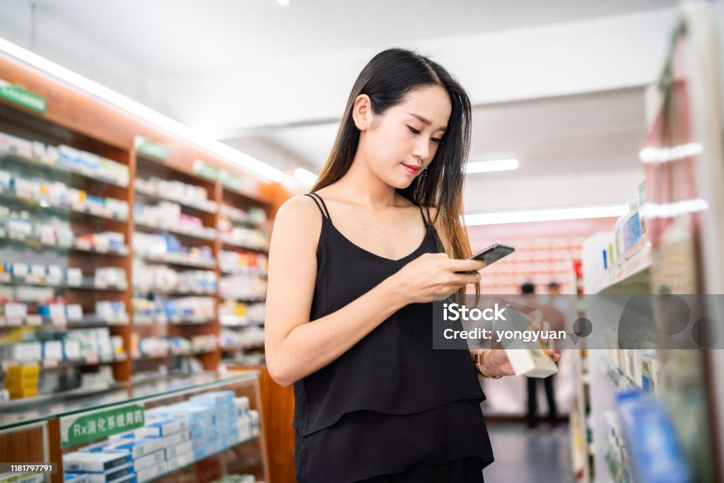 Female customer using a smart phone to scan QR code on a medicine box Female customer using a smart phone to scan QR code on a medicine box. Bar Code Reader Stock Photo