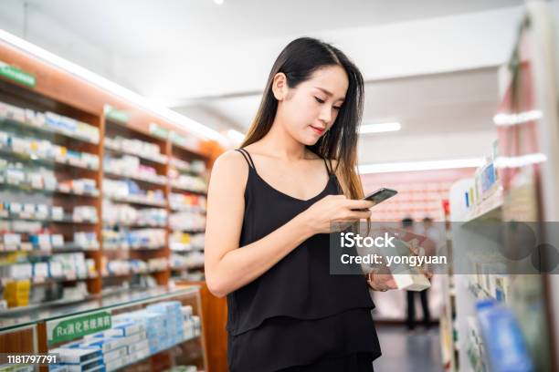 Female Customer Using A Smart Phone To Scan Qr Code On A Medicine Box Stock Photo - Download Image Now