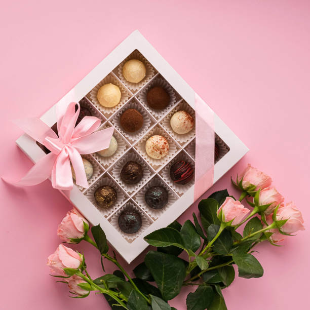 istock Chocolates from various Belgian chocolate in a festive box on a pink background a bouquet roses. Exclusive dessert gift. 1181798665