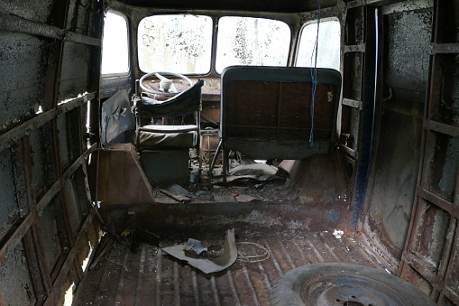The interior of an old and rusty van.