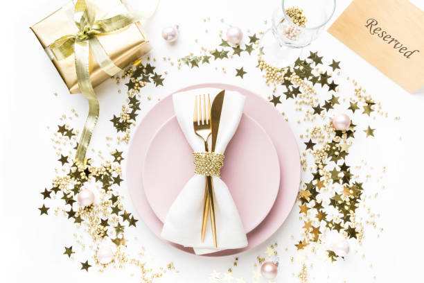 istock Christmas table setting with pink dishware, golden silverware on white background. Top view. 1181800944