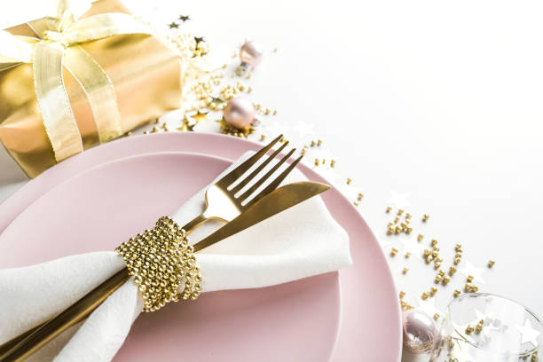istock Christmas elegance table setting with pink dishware, golden silverware on white. Top view. Xmas dinner. 1181800972