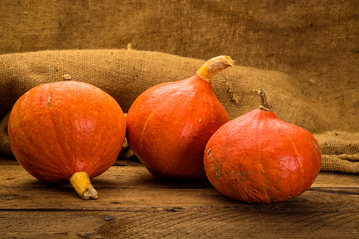 Red Kuri squashes on rustic wooden table