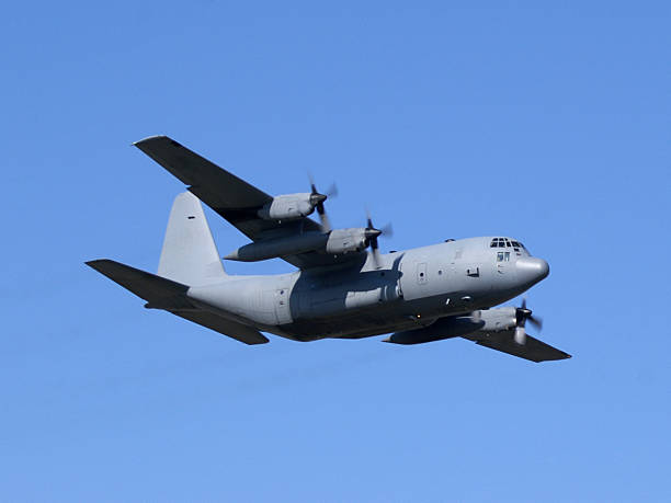 military cargo airplane Lockheed C130 Hercules flying in blue sky stock photo