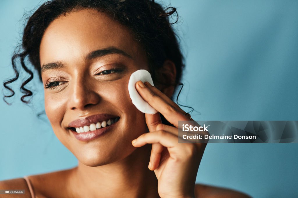 Healthy skin is not an over night process Studio shot of a beautiful young woman using a cotton pad on her face Facial Cleanser Stock Photo