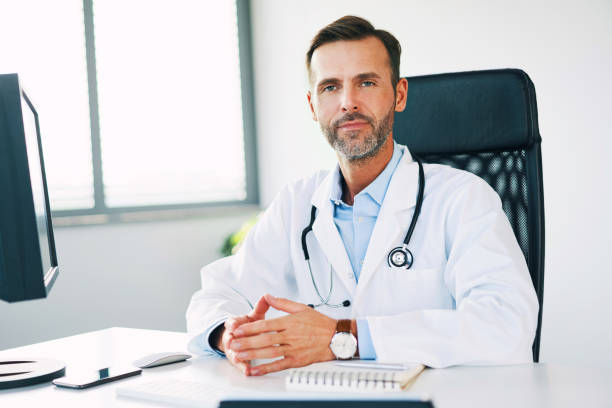 istock Handsome confident doctor sitting in office and looking at camera 1181808935