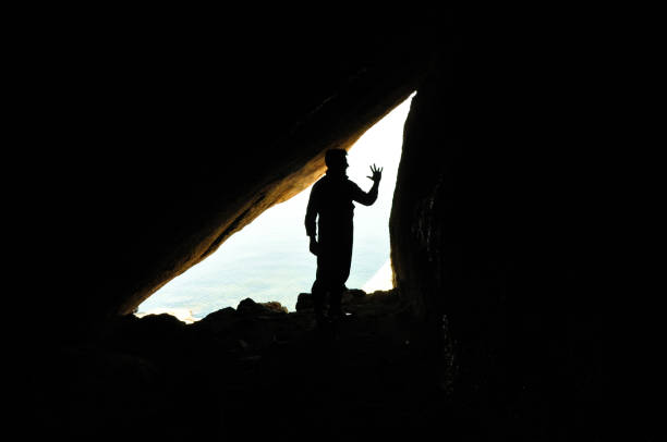 istock A biologist in field work, scientist, silhouette of man inside cave, reverse light, background 1181810838