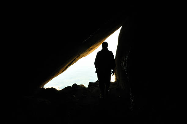 istock A biologist in field work, scientist, silhouette of man inside cave, reverse light, background 1181810840