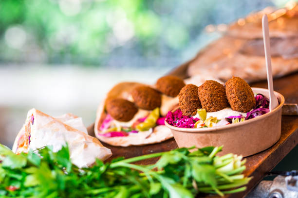 Fresh falafel and salad on display at vegetarian vegan stall at food market Horizontal color close up image depicting a food stall at a street food market in London, UK, selling fresh vegetarian take away food. The food on display includes fresh salad and falafel. Focus on foreground with background blurred out of focus. cafeteria sandwich food healthy eating stock pictures, royalty-free photos & images