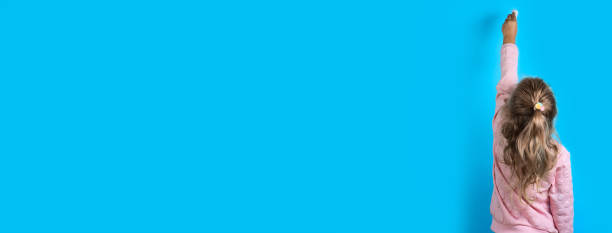 istock Cute girl with white chalk on a blue background. 1181815643