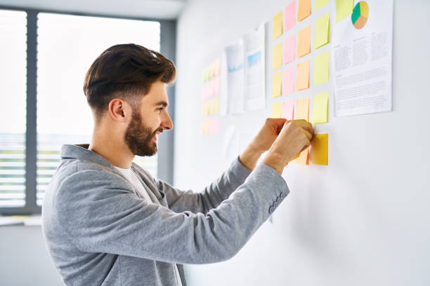istock Young entrepreneur sticking note to wall in office 1181817044