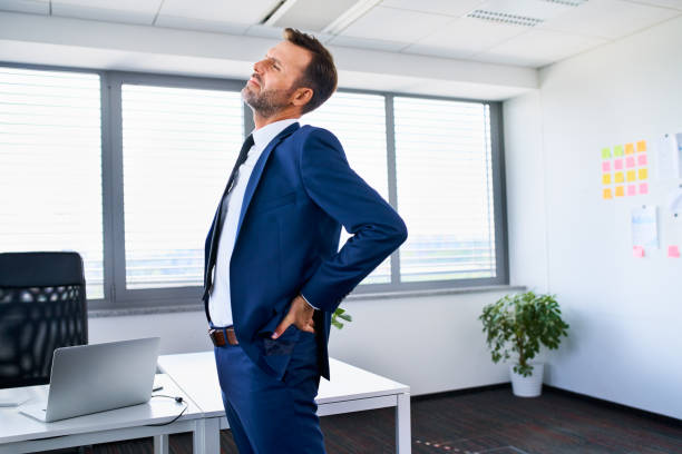 Lower back pain. Businessman stretches in office. Lower back pain. Businessman stretches in office. lower back pain stock pictures, royalty-free photos & images