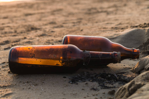 Old beer bottles on the beach. Pollution concept picture. Wastes and garbage in the sand.