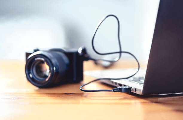 kamera mit laptop mit usb-kabel verbunden. dateiübertragung von dslr auf den computer. - digitalkamera stock-fotos und bilder