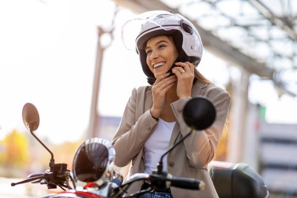 スクーターの女性はヘルメットを締めます - バイクヘルメット ストックフォトと画像