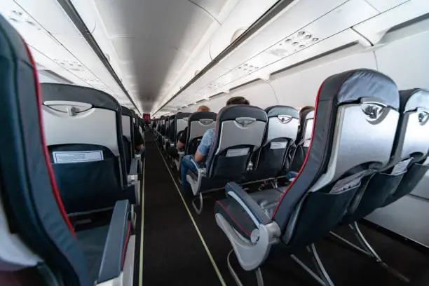 Photo of Airplane cabin seats with passengers. Economy class of new cheapest low-cost airlines without delay or cancellation of flight. Travel trip to another country.