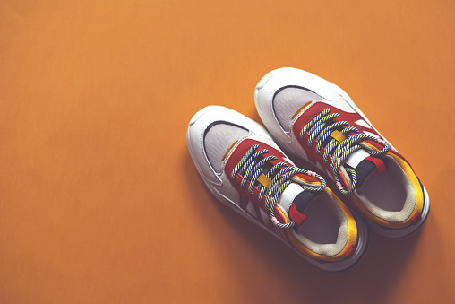 Multi-colored fashion sneakers on a orange background. Sport. There is a place for text.