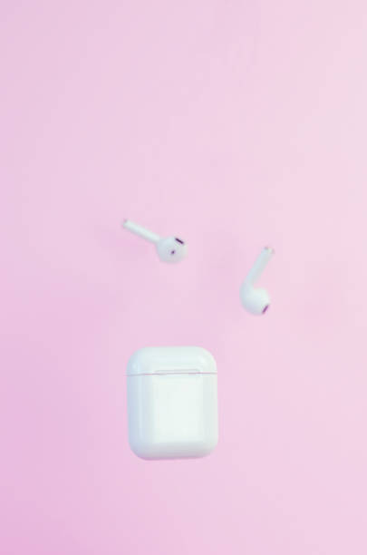 Wireless white headphones with a case on a pink background.