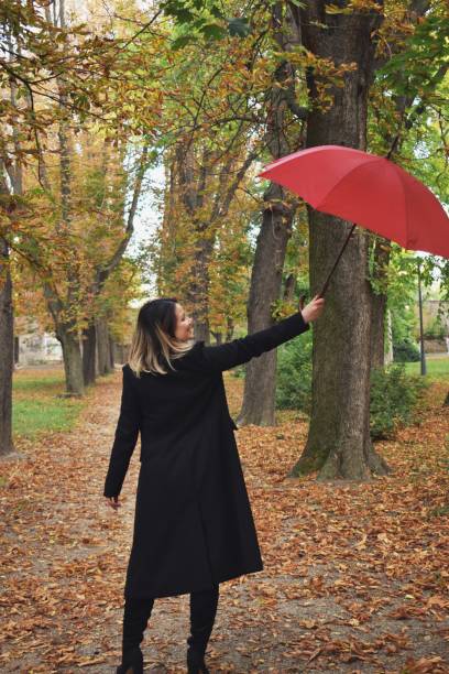 istock Woman outdoors holding red umbrella 1181830561