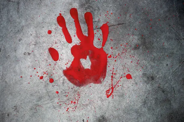 Photo of Red bloody footprint of a hand with bloody spray on a black background. Horror, mysticism, background for halloween