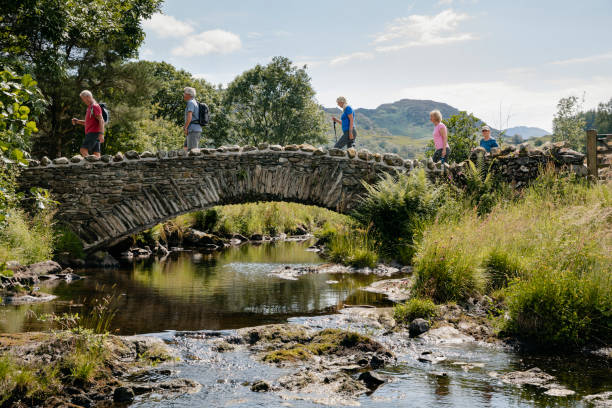 senior friends crossing stone bridge. - bridge people fun river imagens e fotografias de stock