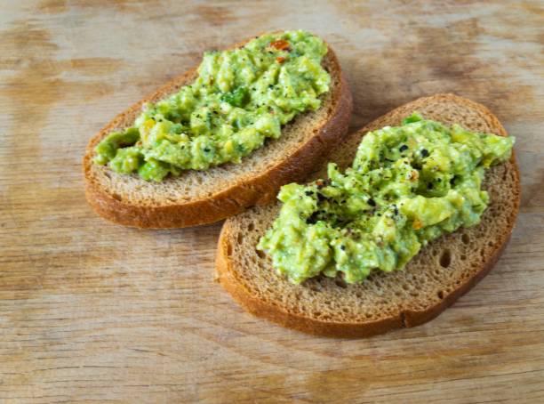 istock Top view on cut board with two  sandwiches with guacamole 1181844331