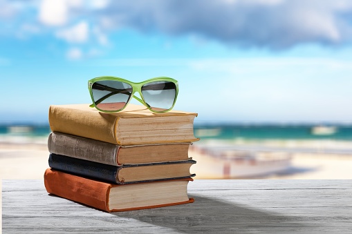 Books and sunglasses  on  beach background