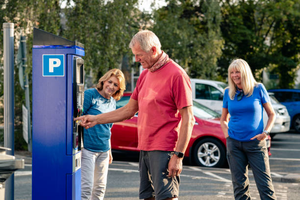 Three adults at ticket machine paying for ticket.